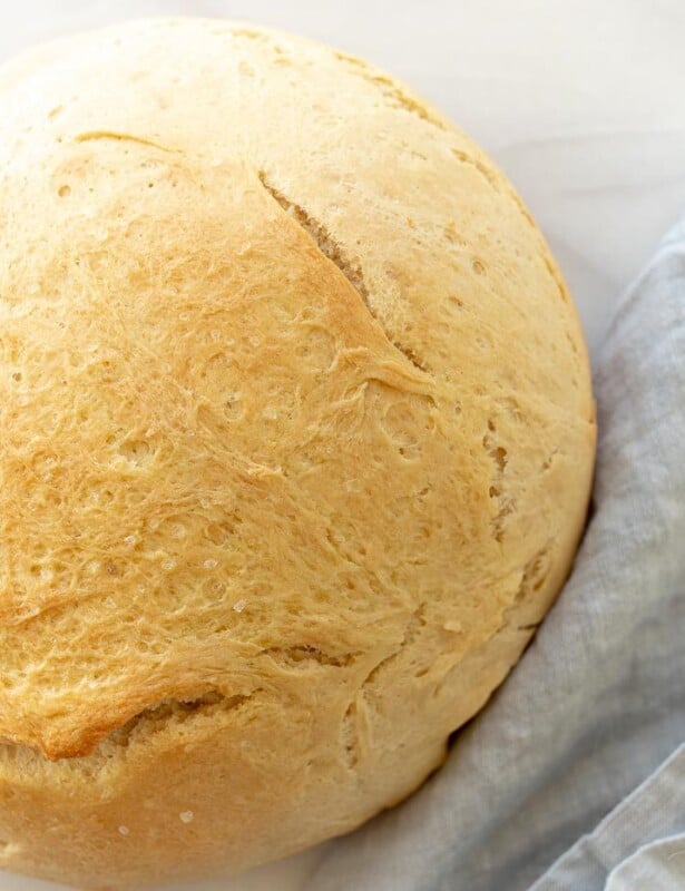 一条圆形的面包，用速溶酵母在大理石表面，蓝色亚麻餐巾纸上制成。