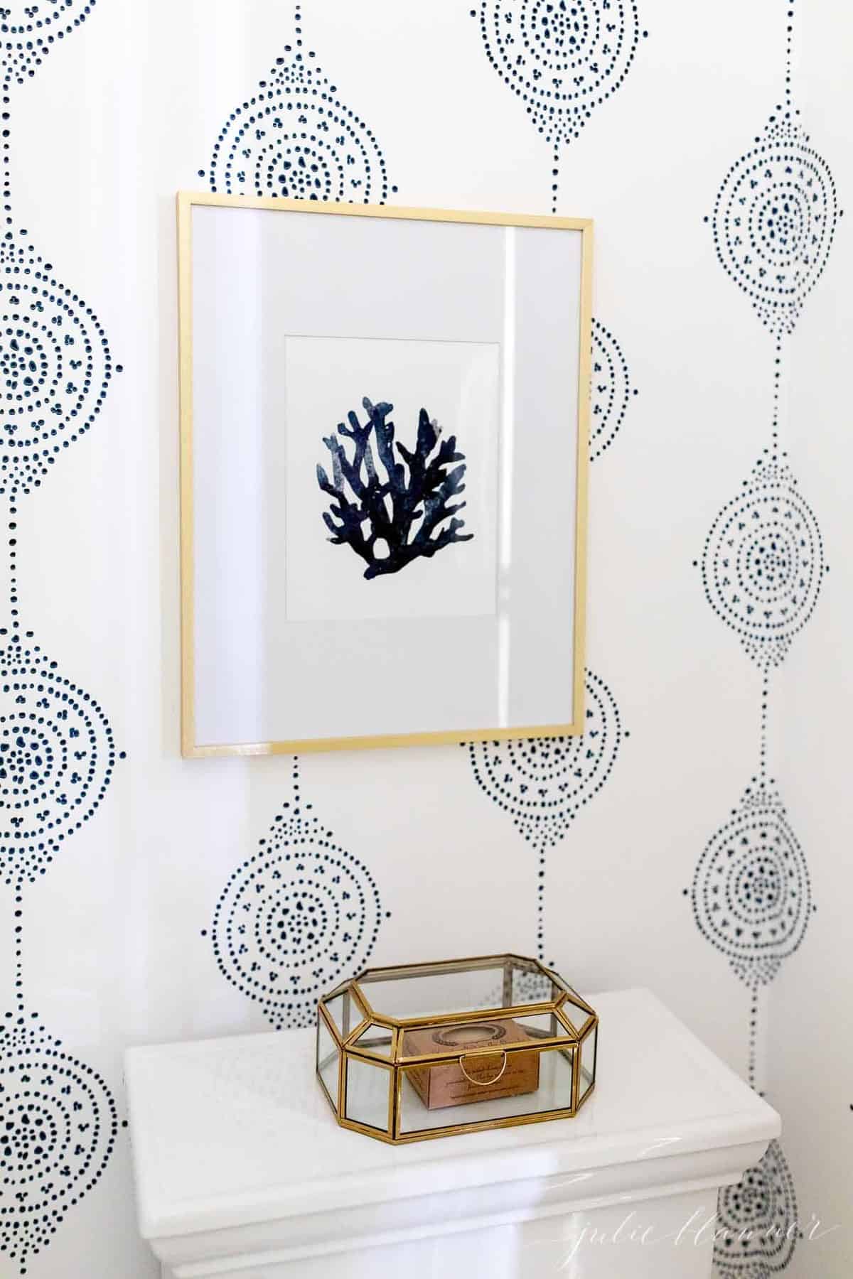 蓝色和白色图案的浴室墙纸，厕所上有贝壳艺术。