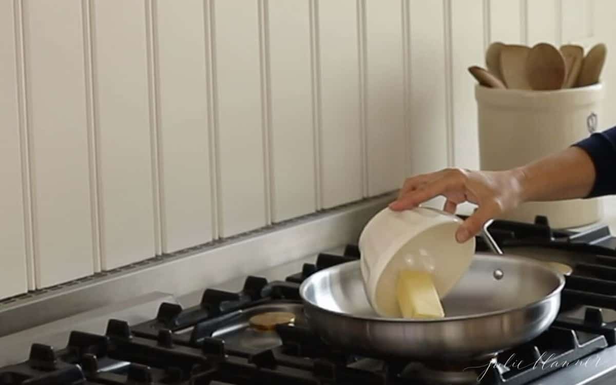 双手将一根黄油放入炉子上的银锅中。GydF4y2Ba