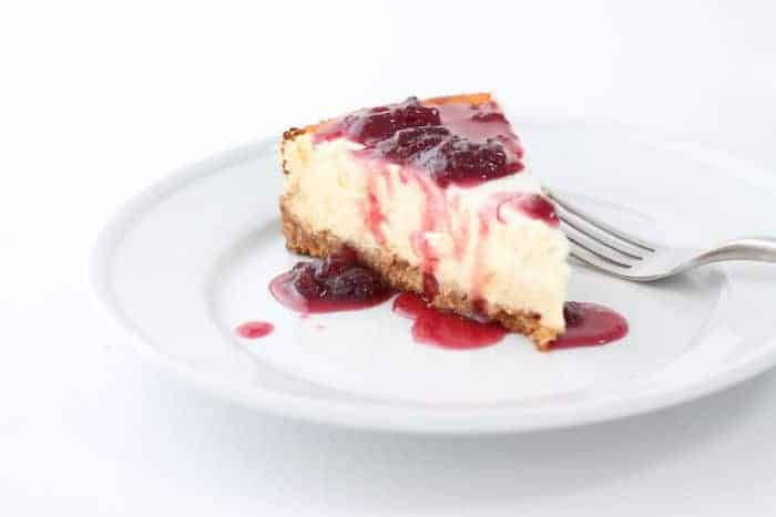 一个白色的背景和白色的地方，上面撒上一片芝士蛋糕，上面撒上草莓馅料，供芝士蛋糕。