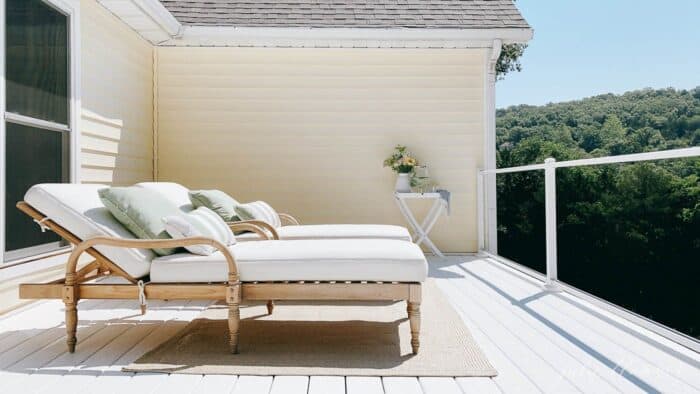 两张木质躺椅放在湖边小屋的白色乙烯基甲板上。