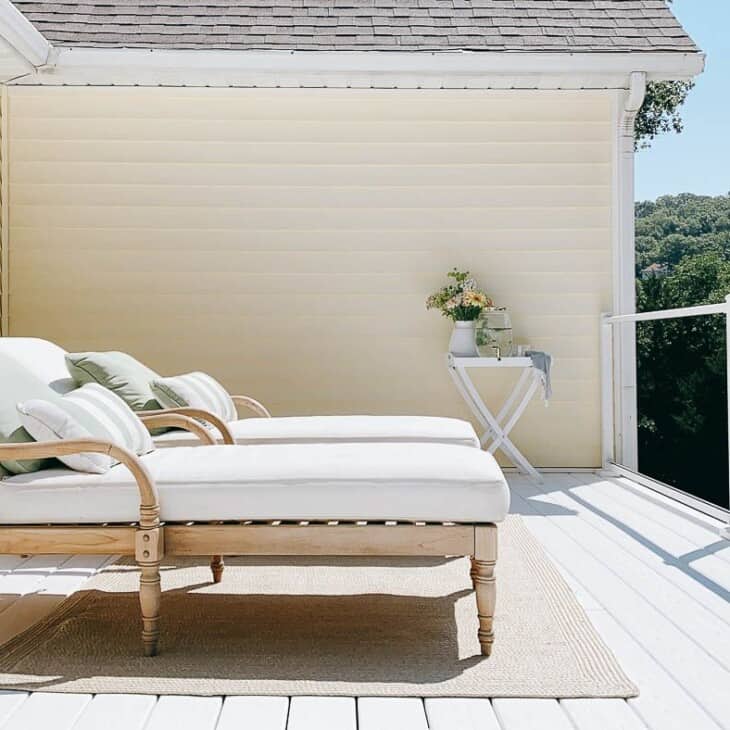 两把木制休息室椅子放在湖泊房屋的白色乙烯基甲板上。
