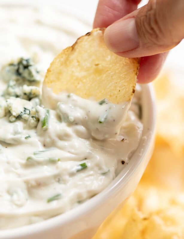 把薯片蘸在白碗里的蓝奶酪里
