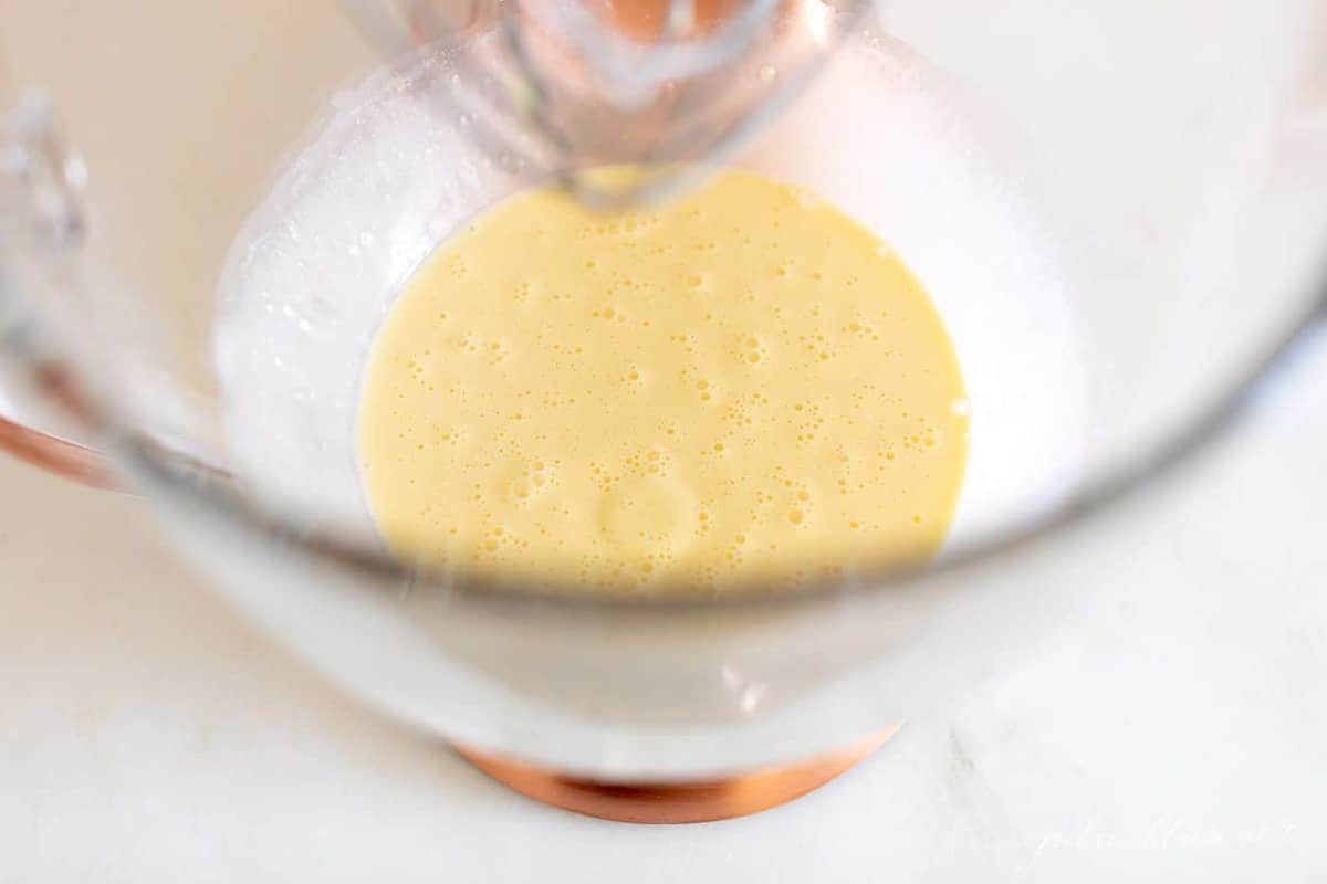 奶油鸡蛋和切达干酪混合在一个玻璃碗的立式搅拌机。gydF4y2Ba