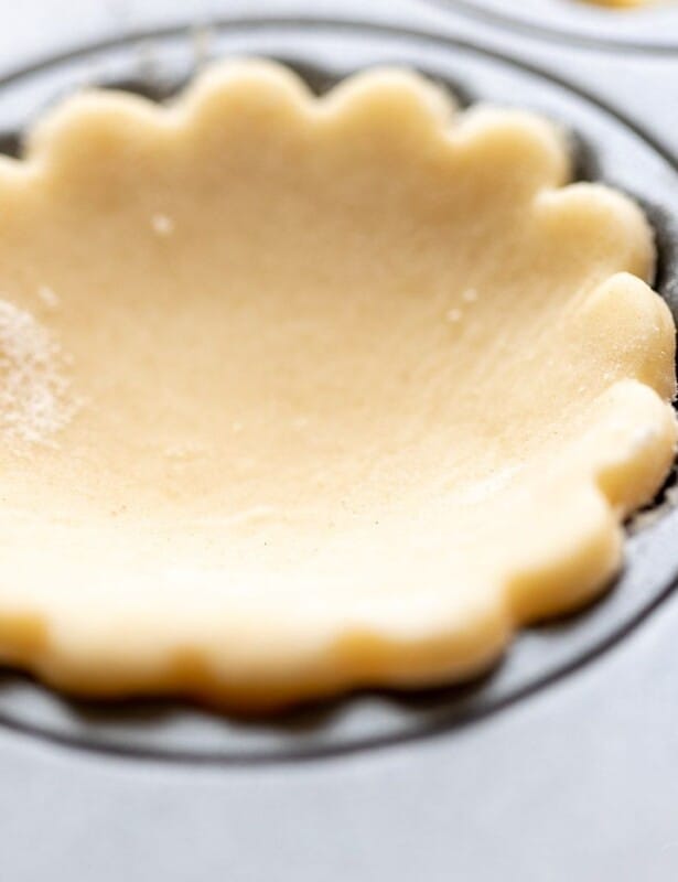 扇形奶油芝士馅饼地壳切出，在松饼锡中休息。