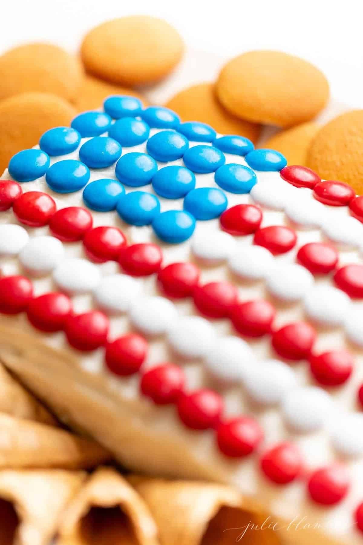 7月4日国旗甜点，上面覆盖着m&ms巧克力豆，周围是饼干。gydF4y2Ba