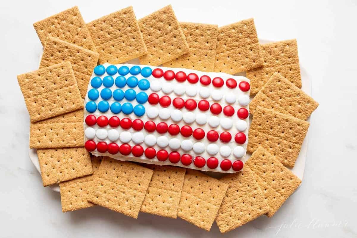 7月4日国旗甜点，上面覆盖着m&ms巧克力豆，周围是饼干。gydF4y2Ba