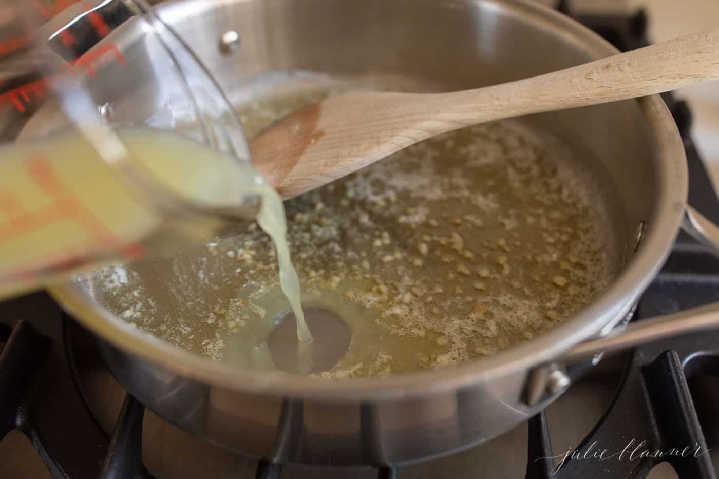 炉子上的银锅，用木铲搅拌融化的黄油和大蒜。gydF4y2Ba
