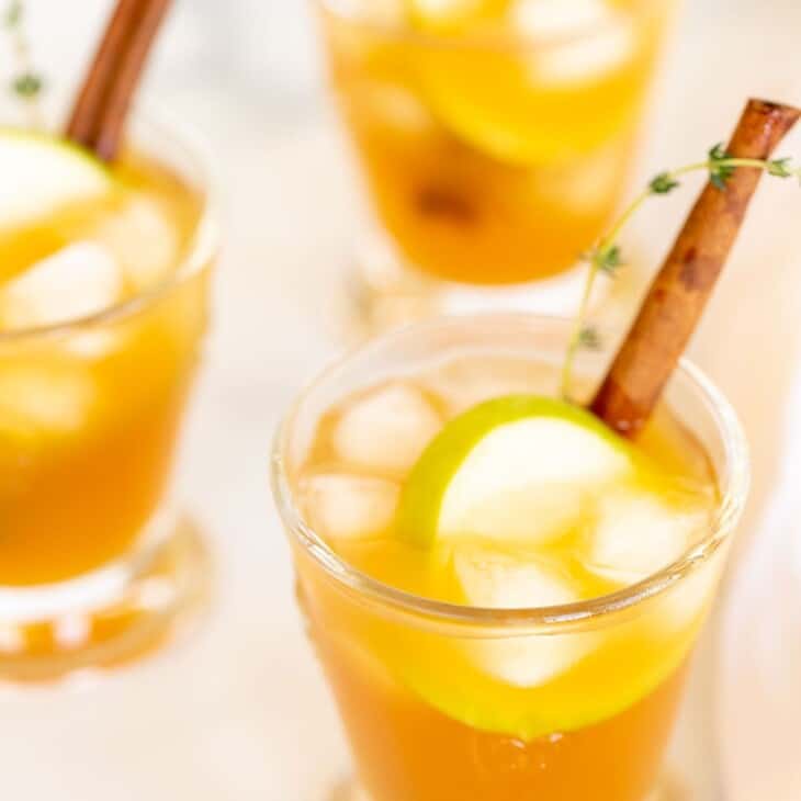 鸡尾酒杯内盛有加冰的苹果酒鸡尾酒，饰以百里香、肉桂棒和苹果片。