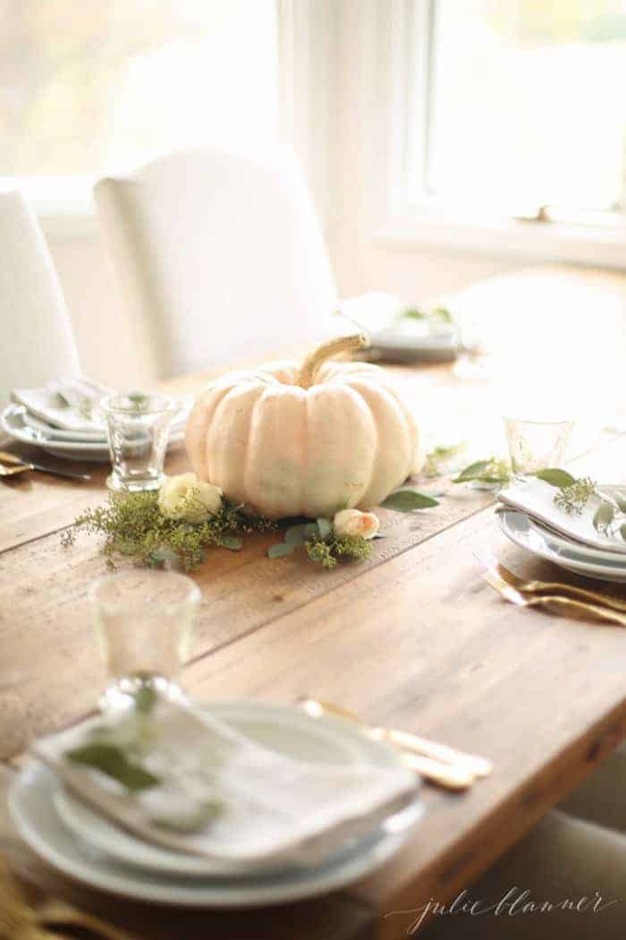 为秋季派对准备的木制农场餐桌，白色南瓜和鲜花作为秋季中心摆设。