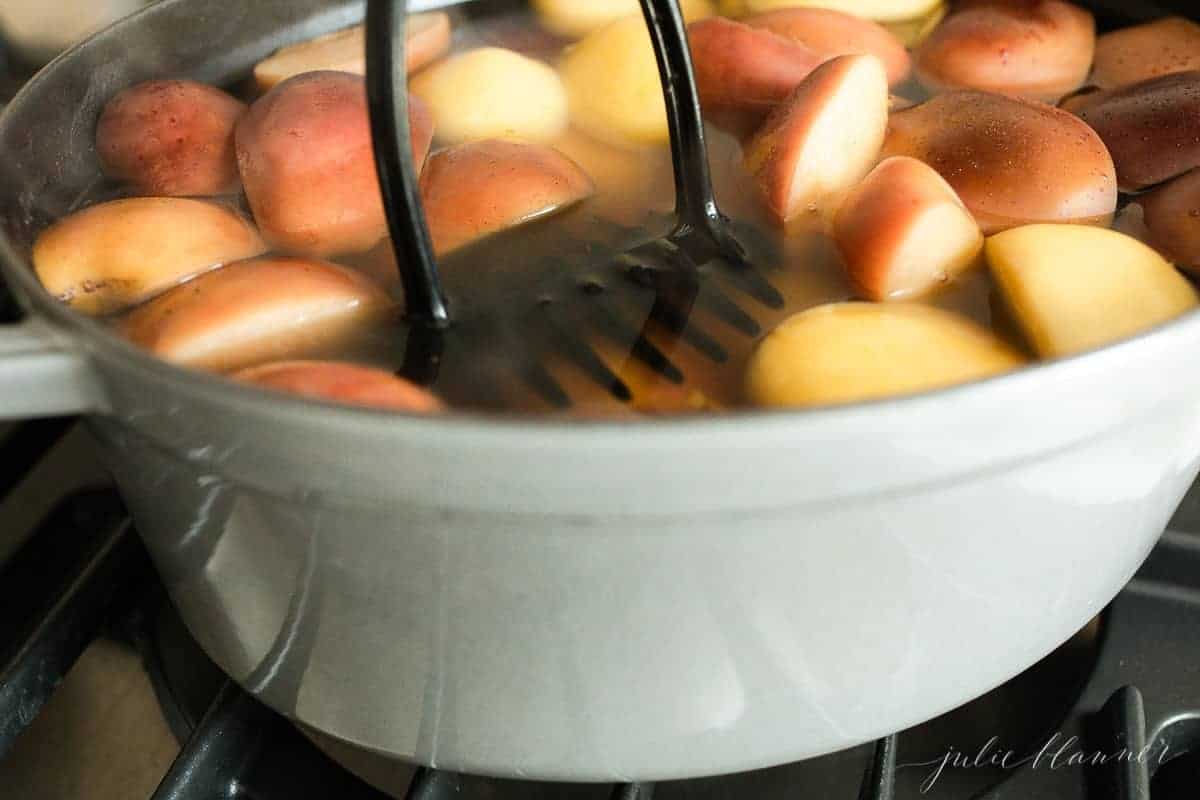 特写镜头，切片的苹果在一锅水里，煮成自制的苹果酒配方，在锅里捣碎土豆。gydF4y2Ba