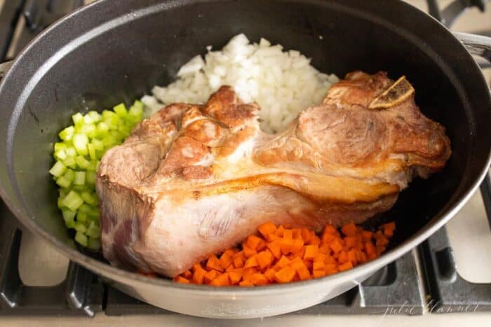 一个灰色铸铁锅，里面有棕色的猪肉和蔬菜，用来做肉酱