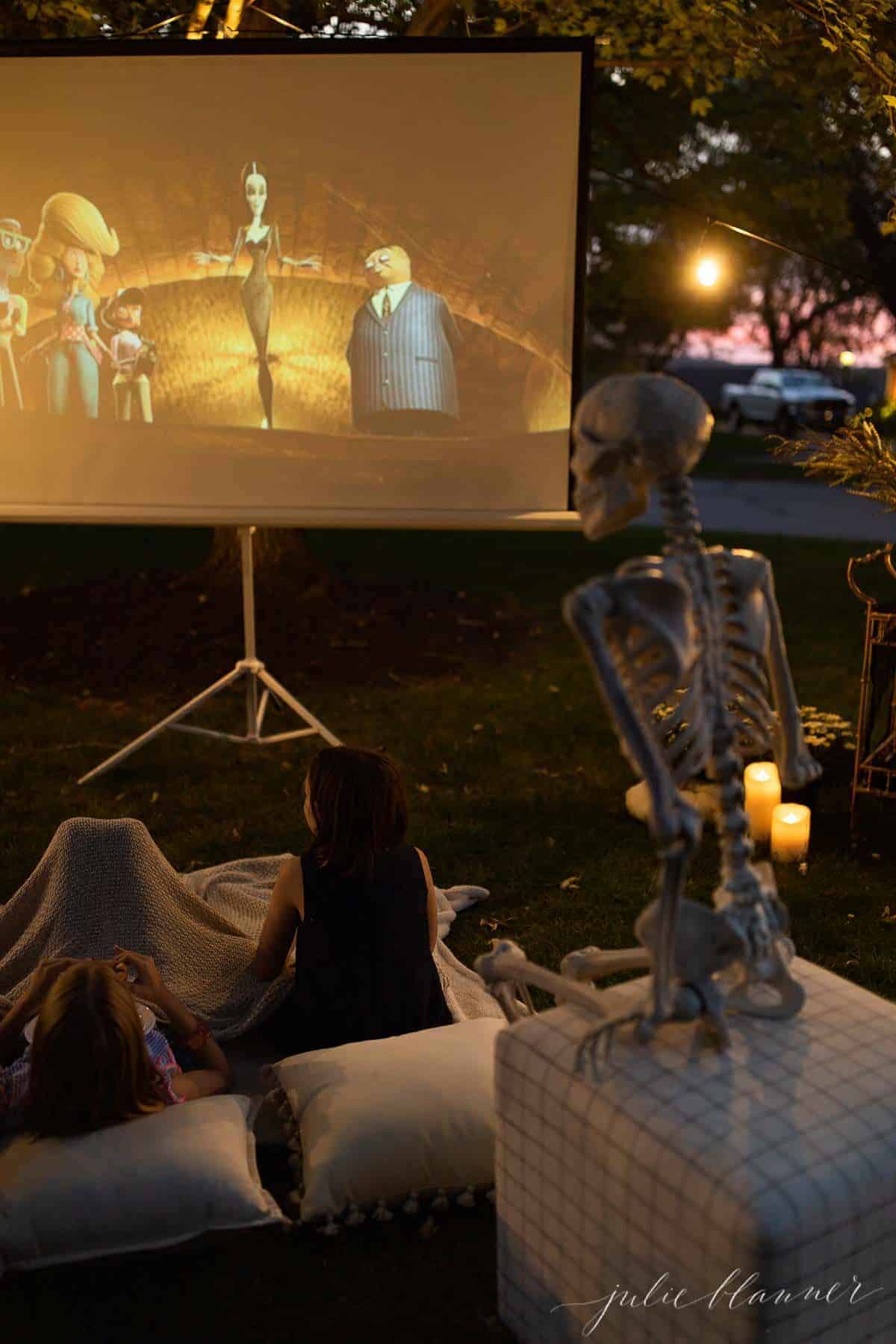 万圣节前夕在院子里布置的户外电影，有骷髅、蜡烛和装饰品。