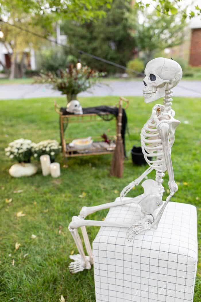 一个骷髅坐在凳子上，背景是一场万圣节派对。