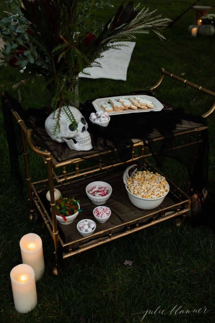 万圣节户外电影夜小吃放在金条车上，背景是鲜花。