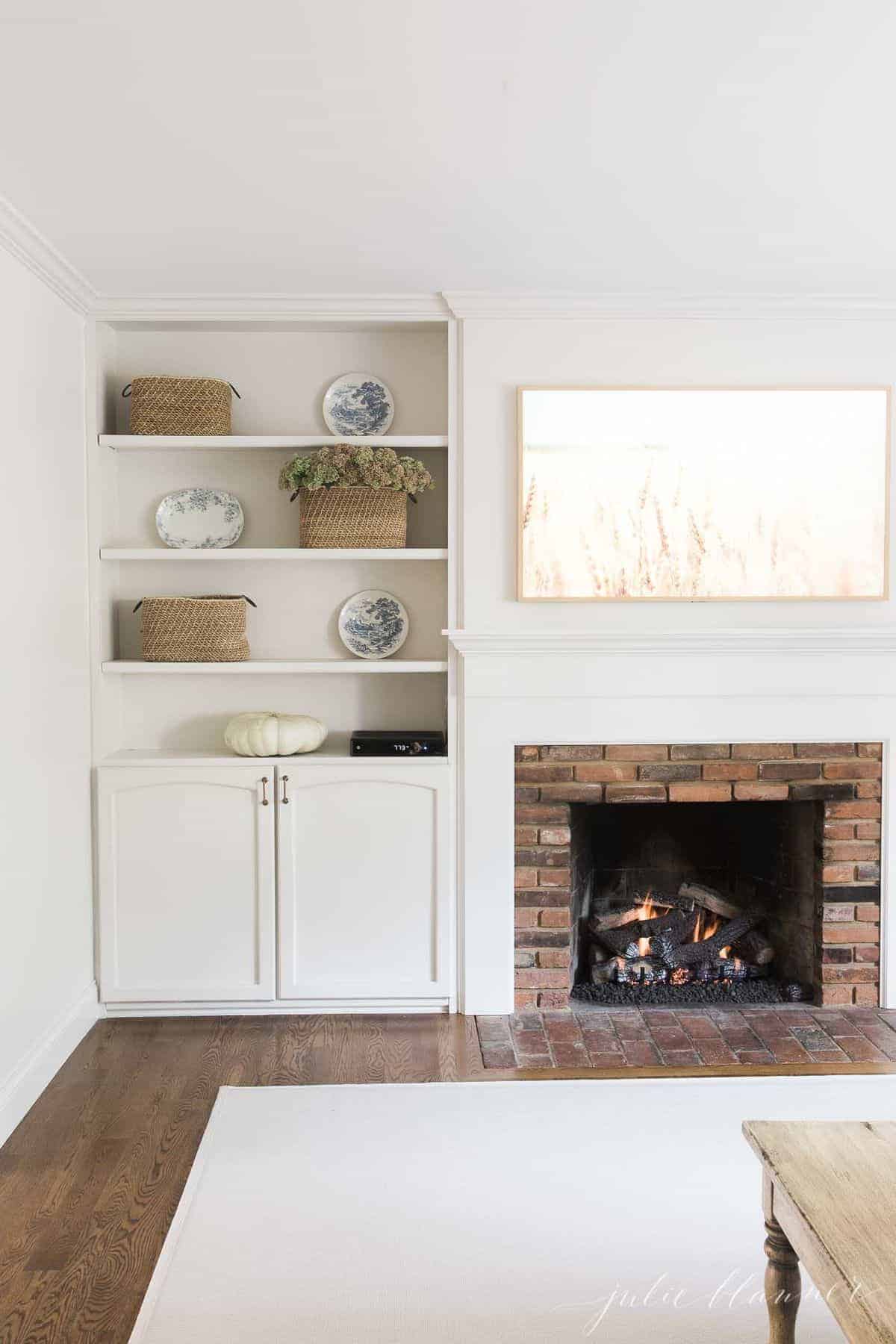 一间白色的客厅，带有壁炉、嵌入式家具和硬木地板上的客厅地毯。
