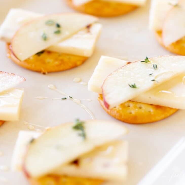 奶酪和饼干展示，苹果堆在切达干酪上。