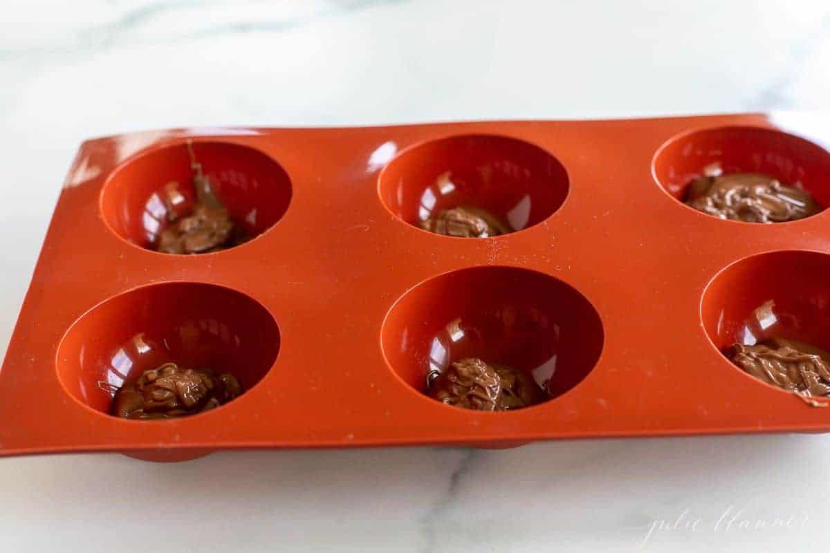 红色硅胶球模具内融化的巧克力热巧克力炸弹配方教程。gydF4y2Ba
