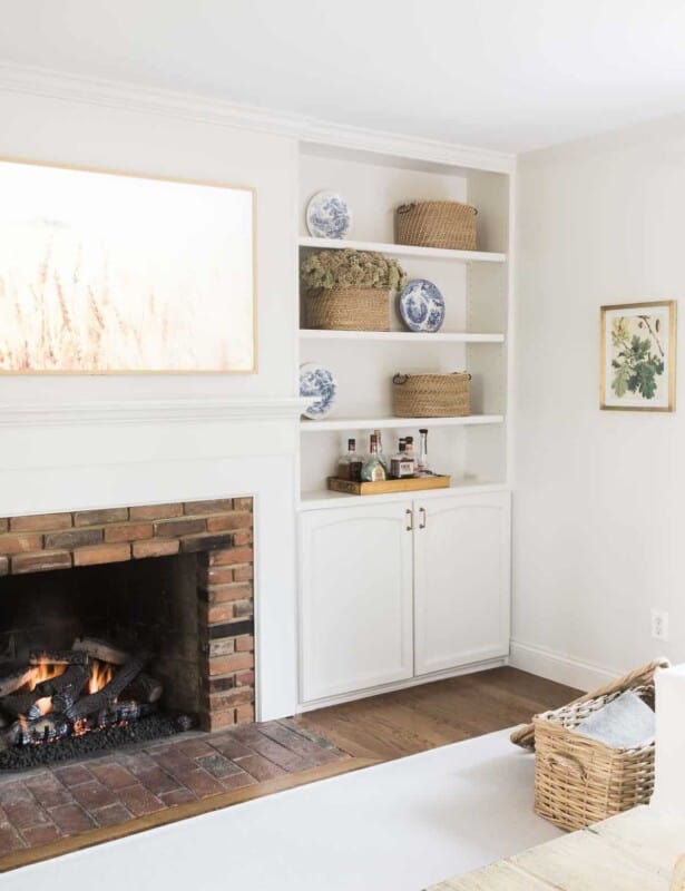 一个白色的客厅，上面有壁炉，内置书架和硬木地板上的客厅地毯。