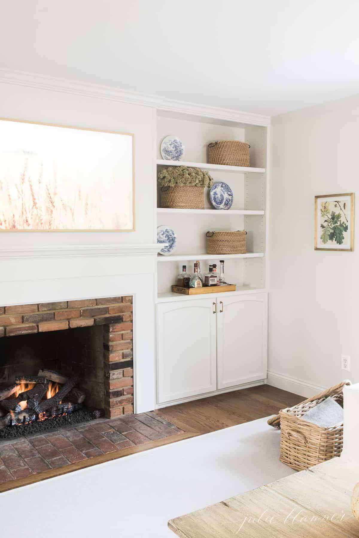 一间带壁炉、内置书架的白色客厅，硬木地板上铺着客厅地毯。