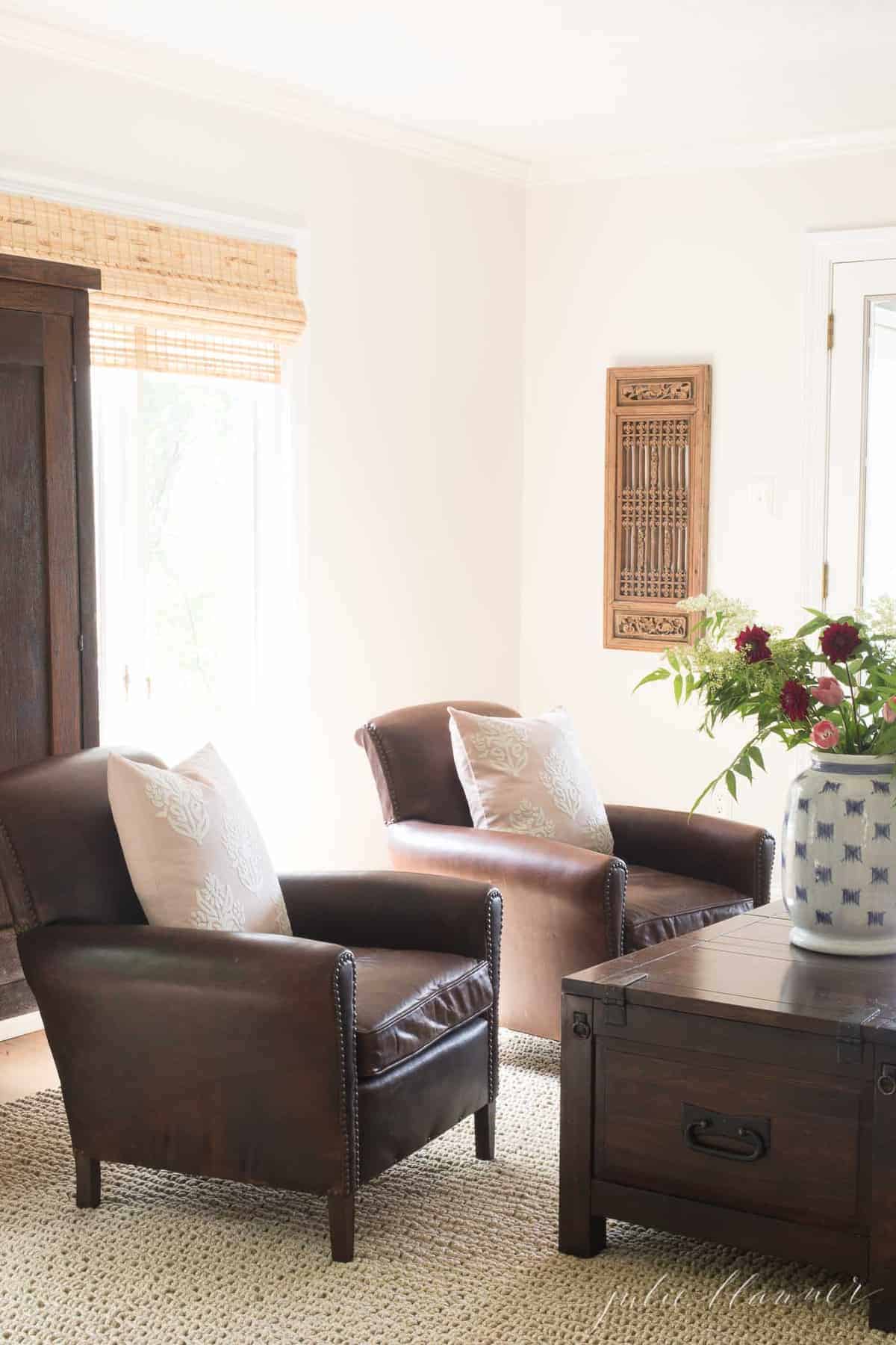 一间白色的家庭娱乐室，配有真皮椅子和客厅的大地毯。