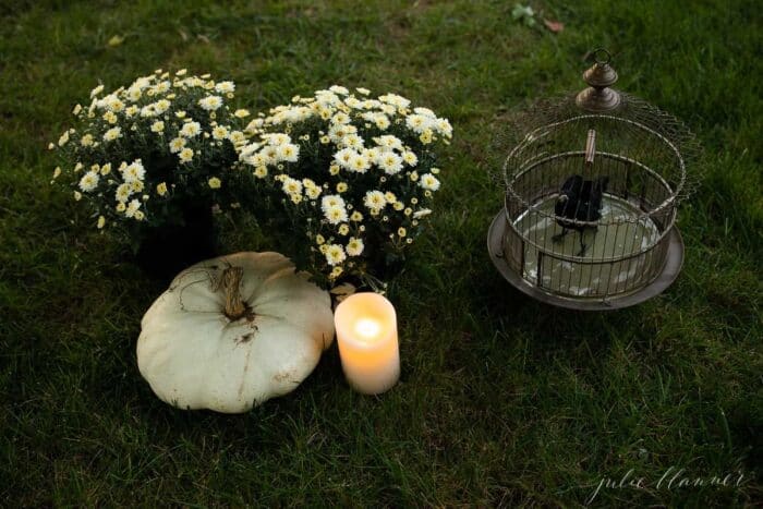 草地上摆放着妈妈、传家宝蜡烛和女巫的扫帚，作为万圣节的装饰。