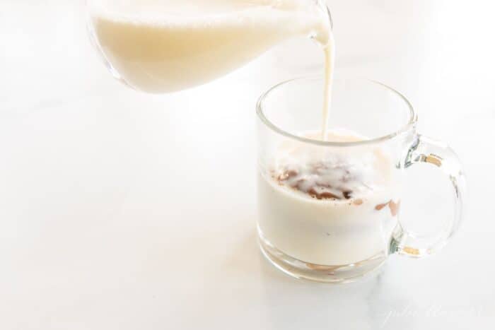 一个装满花生酱热巧克力的玻璃杯，上面是迷你棉花糖，上面倒了一小块蒸牛奶。GydF4y2Ba