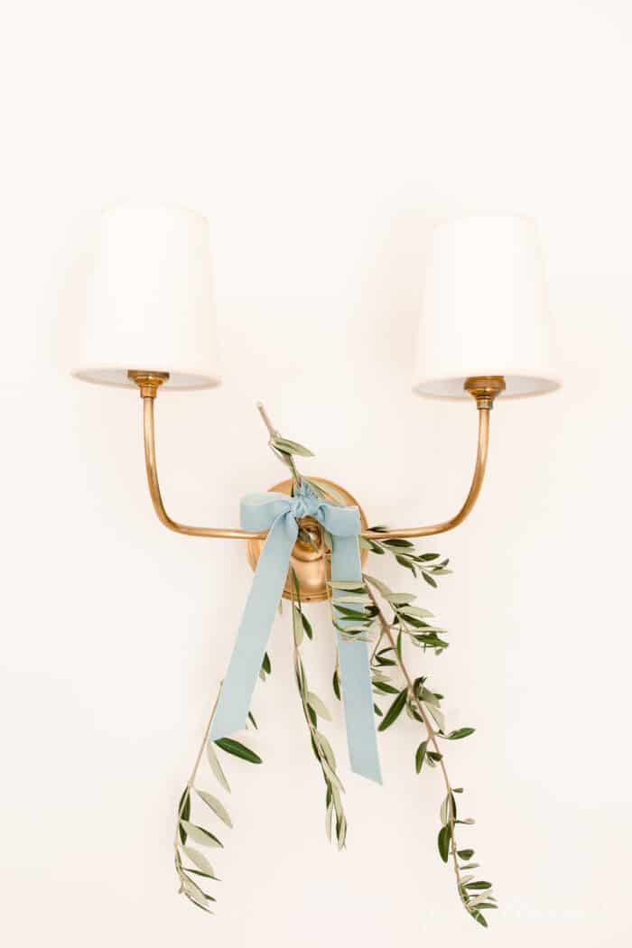 用蓝色缎带系上橄榄枝的黄铜双枝壁式烛台，适合斯堪的纳维亚人的圣诞之旅。