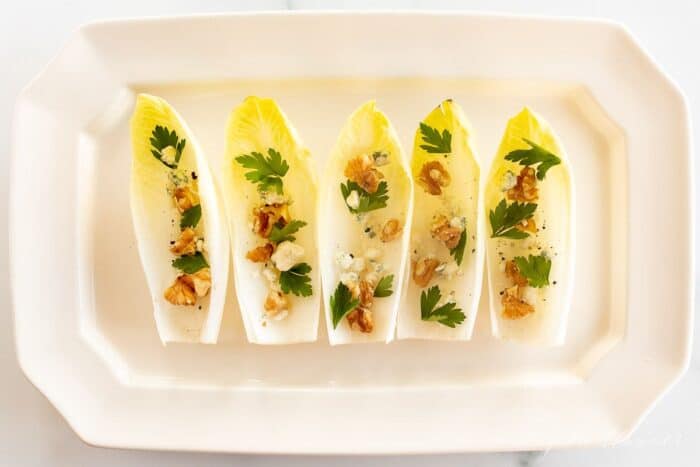 一个白色浅盘单独的菊苣莴苣叶，填满坚果，奶酪和更多菊苣沙拉开胃菜。gydF4y2Ba