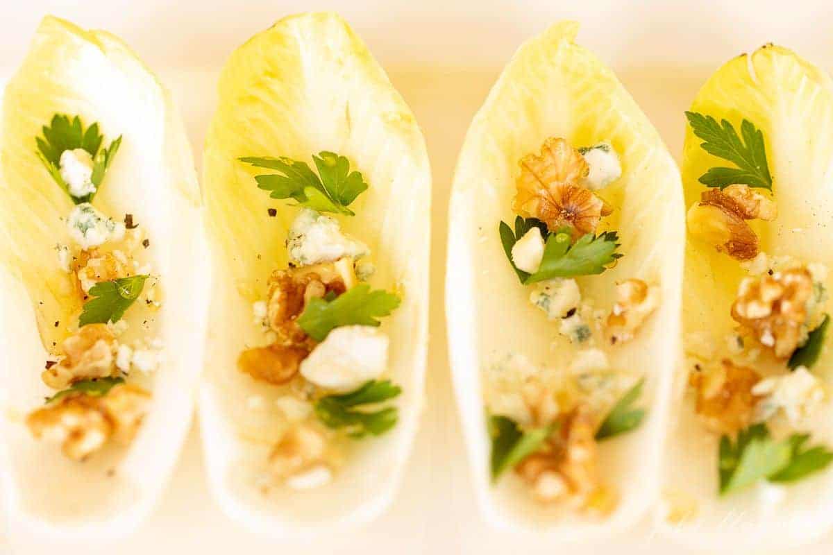 一个白色的浅盘，里面有四片单独的菊苣叶，里面装满了独特的开胃小菜。