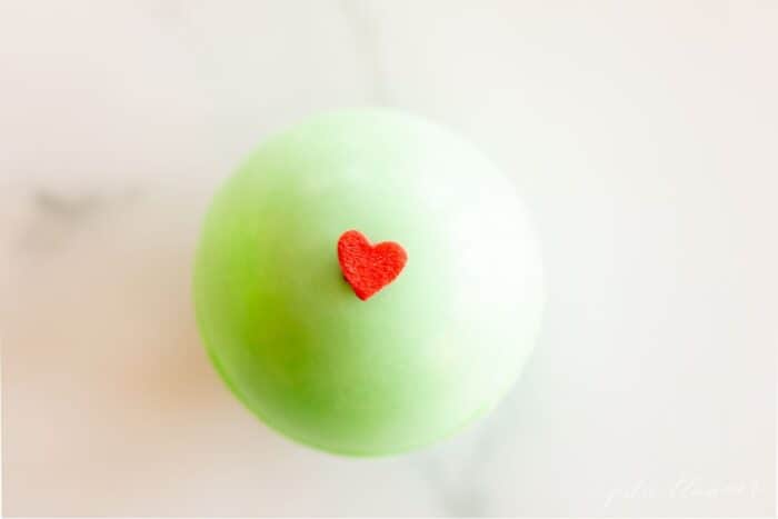 一个绿色的热巧克力炸弹，上面装饰着一颗红色的心，放在大理石表面。gydF4y2Ba