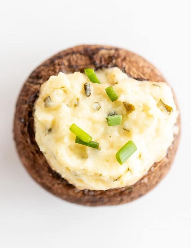 在白色表面上的单个boursin毛绒蘑菇，上面用切块韭菜。