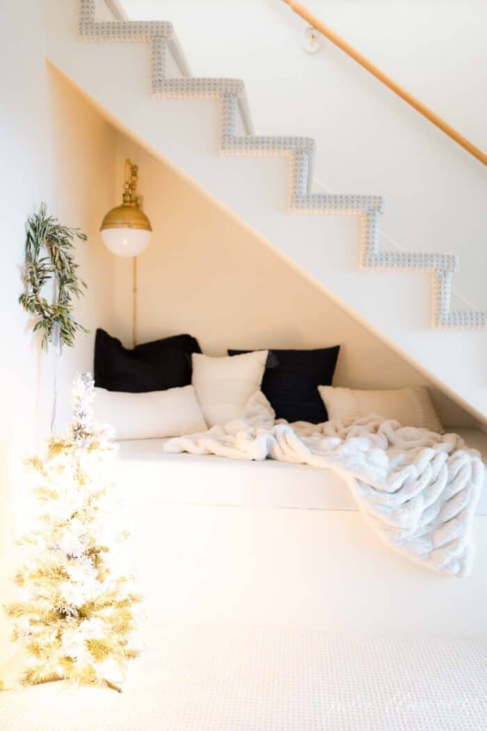 楼梯下的一个小角落，用新鲜的花环和一棵结霜的圣诞树来装饰斯堪的纳维亚式的圣诞节。