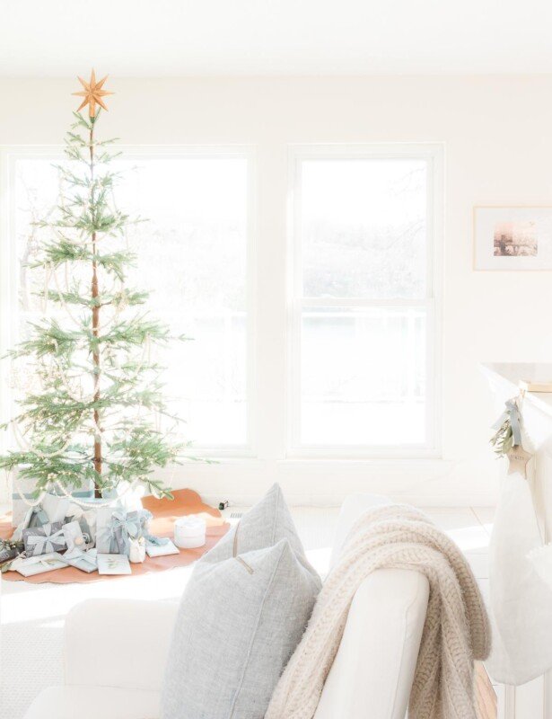 一个白色的客厅穿着西班牙圣诞节，有一棵简单的斯堪的纳维亚树。