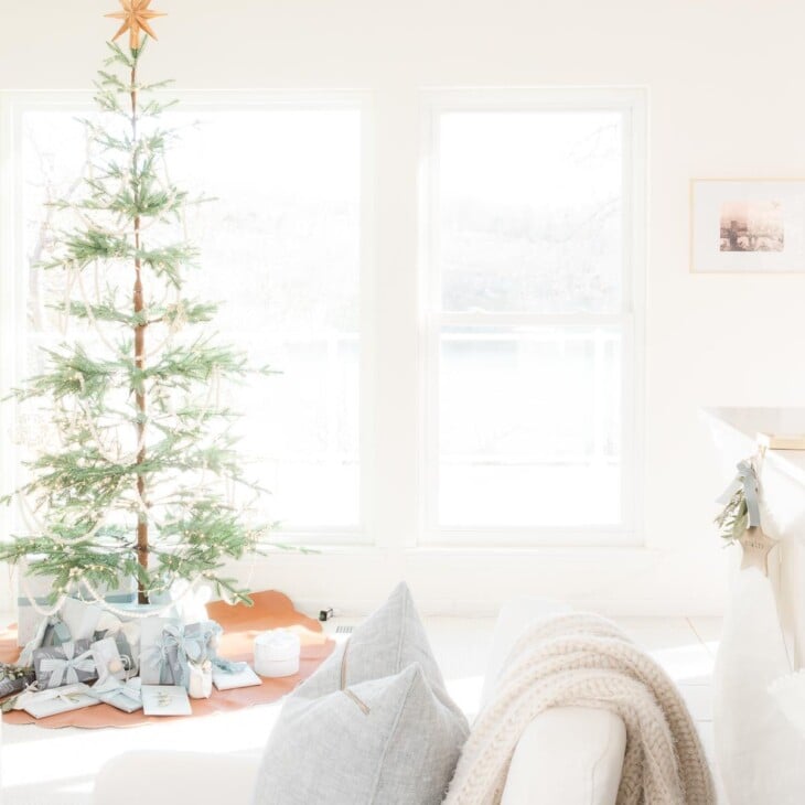 白色的起居室穿着斯堪的纳维亚圣诞节与简单的斯堪的纳维亚树。