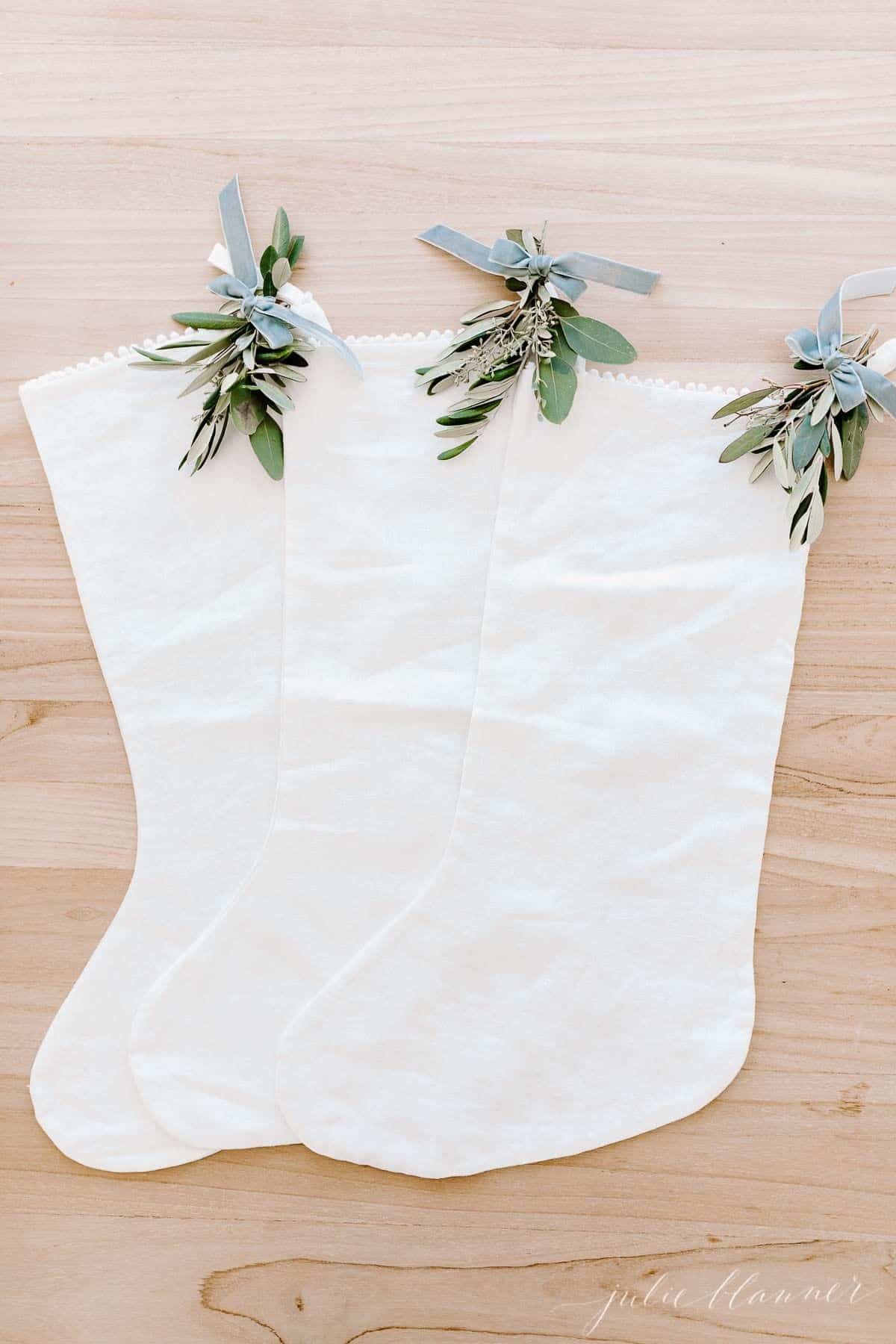 三支带有节日绿色气息的白色亚麻布长袜，放在木质的表面上。