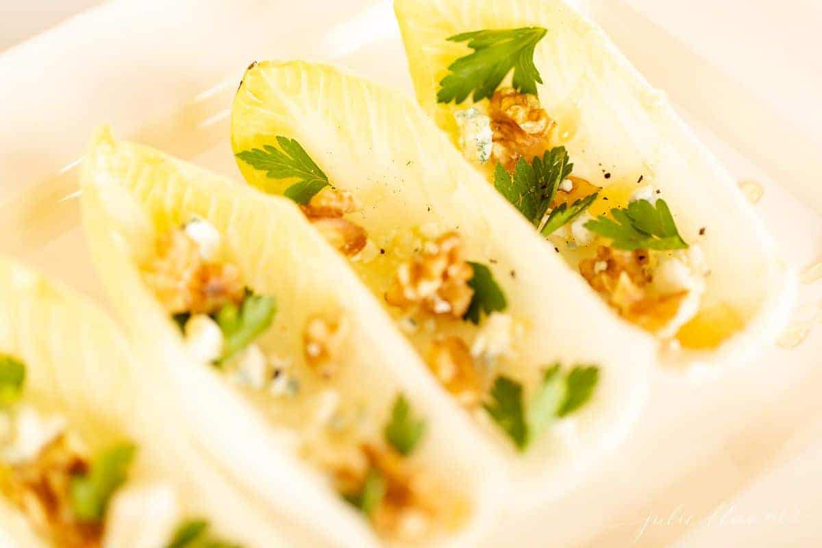 一个健康的感恩节开胃菜形象，一个白色的浅盘，菊苣生菜沙拉，上面放着坚果、奶酪和欧芹vwin官网入口