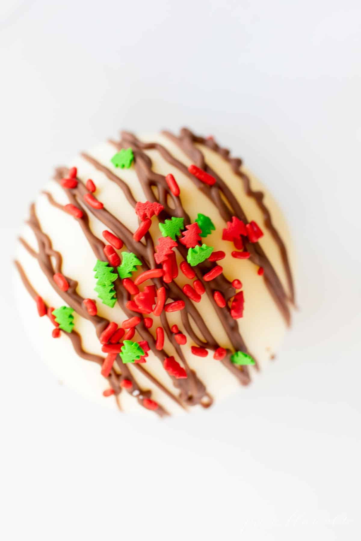 一个白色的盘子，上面有一颗白巧克力热巧克力炸弹，上面有圣诞糖屑。gydF4y2Ba