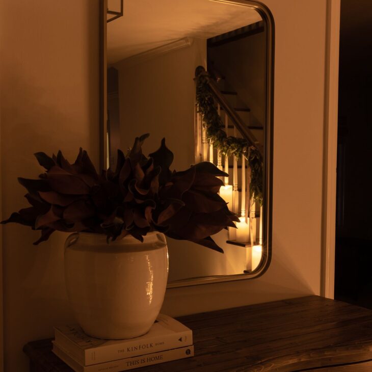 一张入口桌，背景是一个玉兰花花瓶和圣诞彩灯。