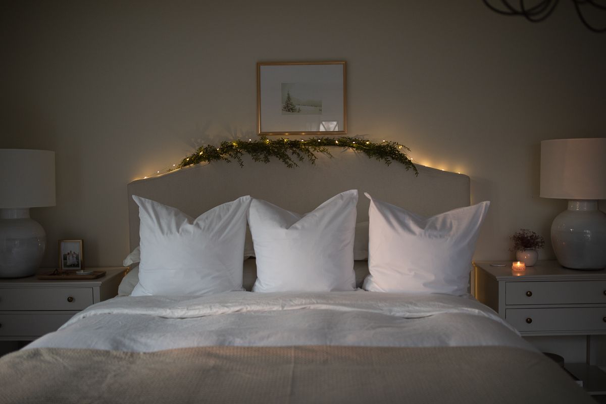 一张白色的床，上面有圣诞花环和彩灯。