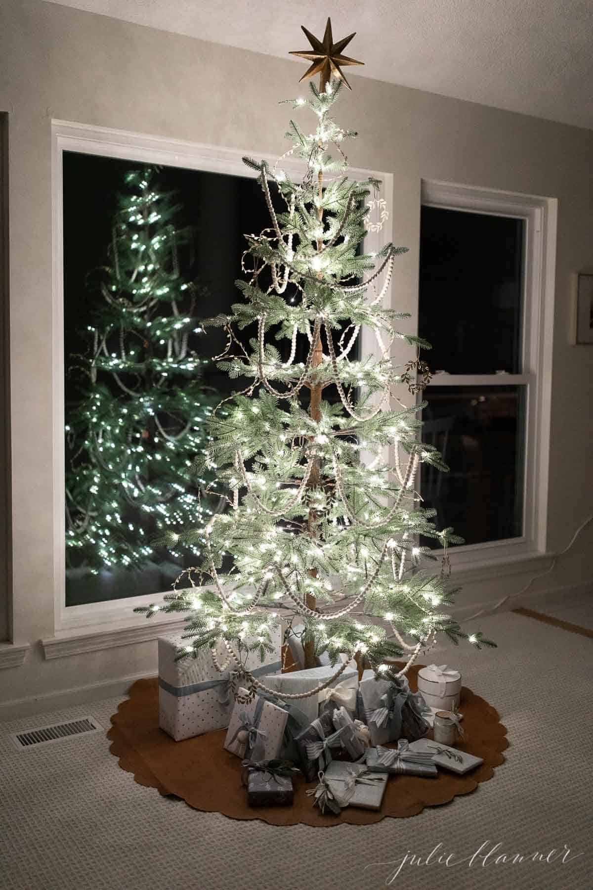 一棵装饰稀疏的斯堪的纳维亚风格的圣诞树映照在窗户上。
