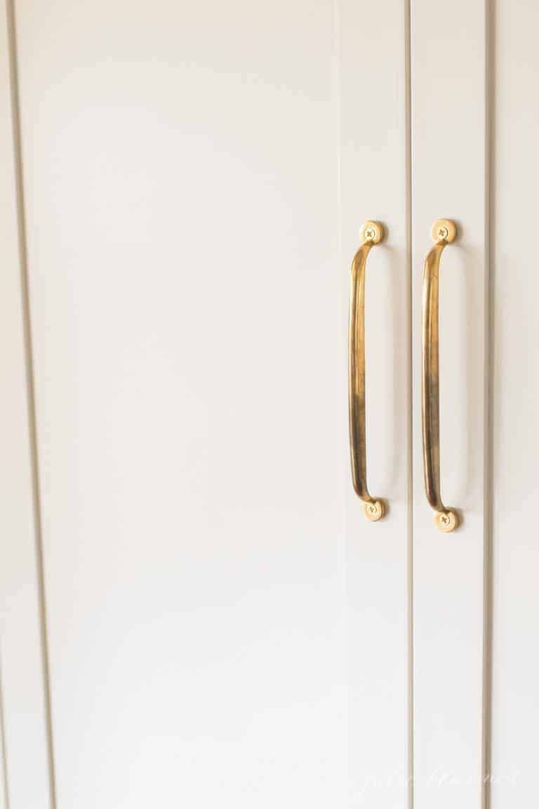 黄铜橱柜把手拉在白色冰箱橱柜上。