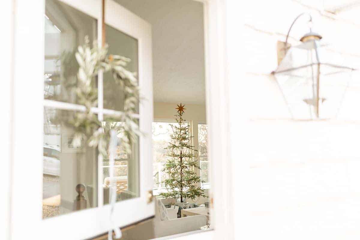 一扇白色的外部荷兰门，张开，看着带有圣诞树的客厅。
