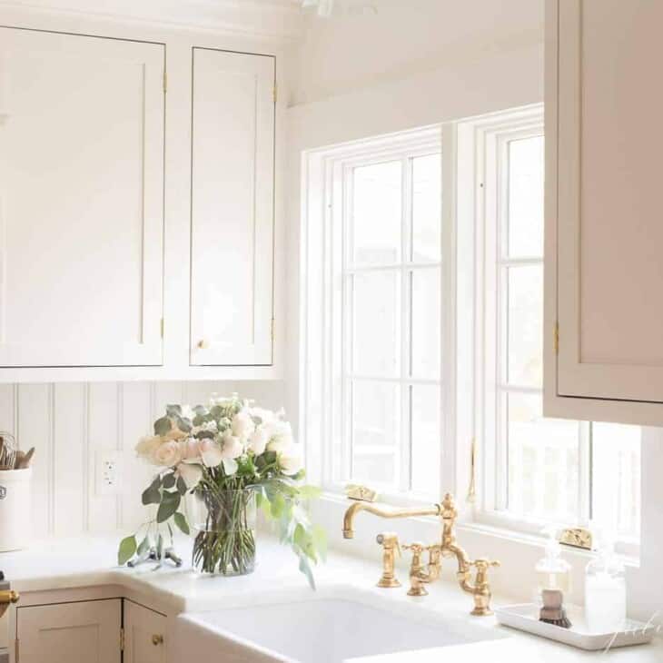 厨房里有奶油色的嵌壁式橱柜，大理石台面和黄铜水龙头。