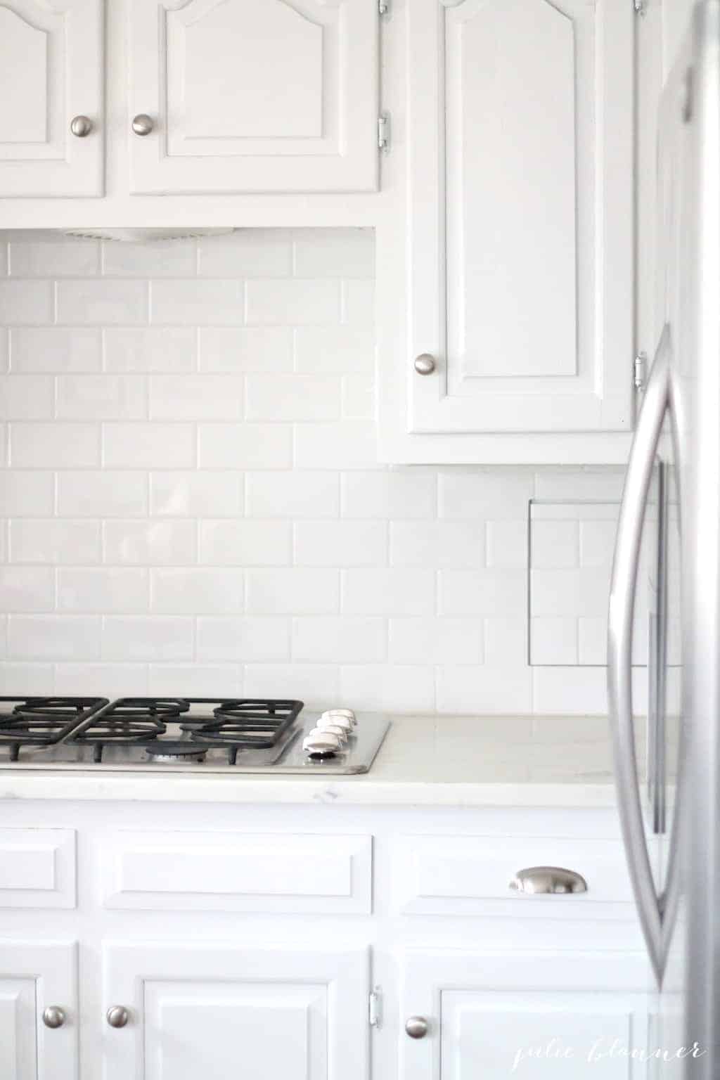白色厨房，后挡板是白色的地铁瓷砖。