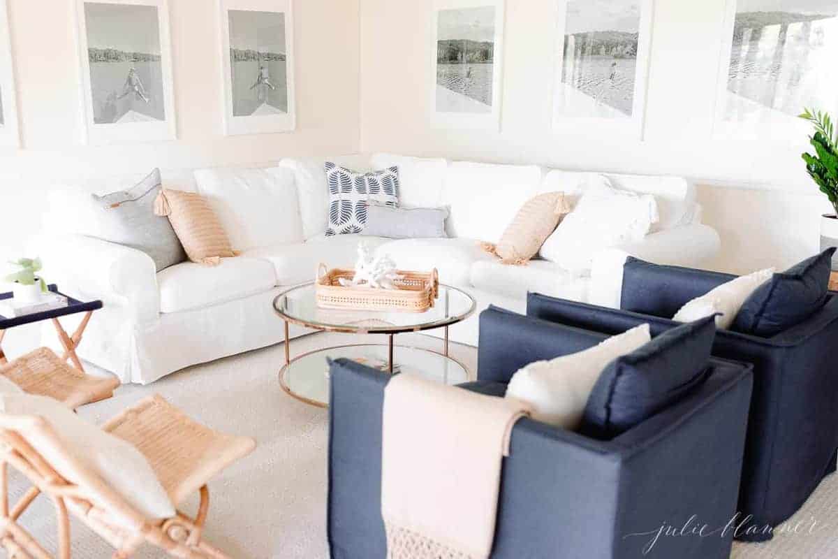 一间现代的白色客厅，墙上挂着大大的黑白照片，白色组合沙发和藏青色椅子。