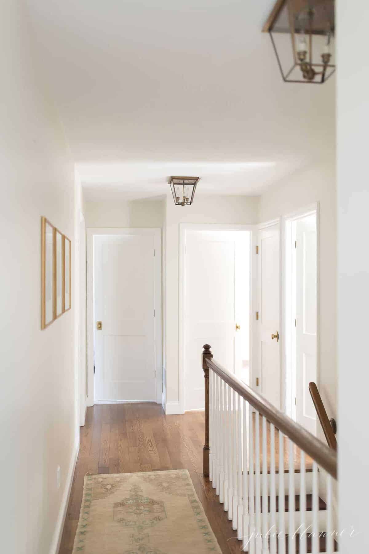 一条白色的走廊，铺着木地板，还有带黄铜门把手的震动派风格的门。