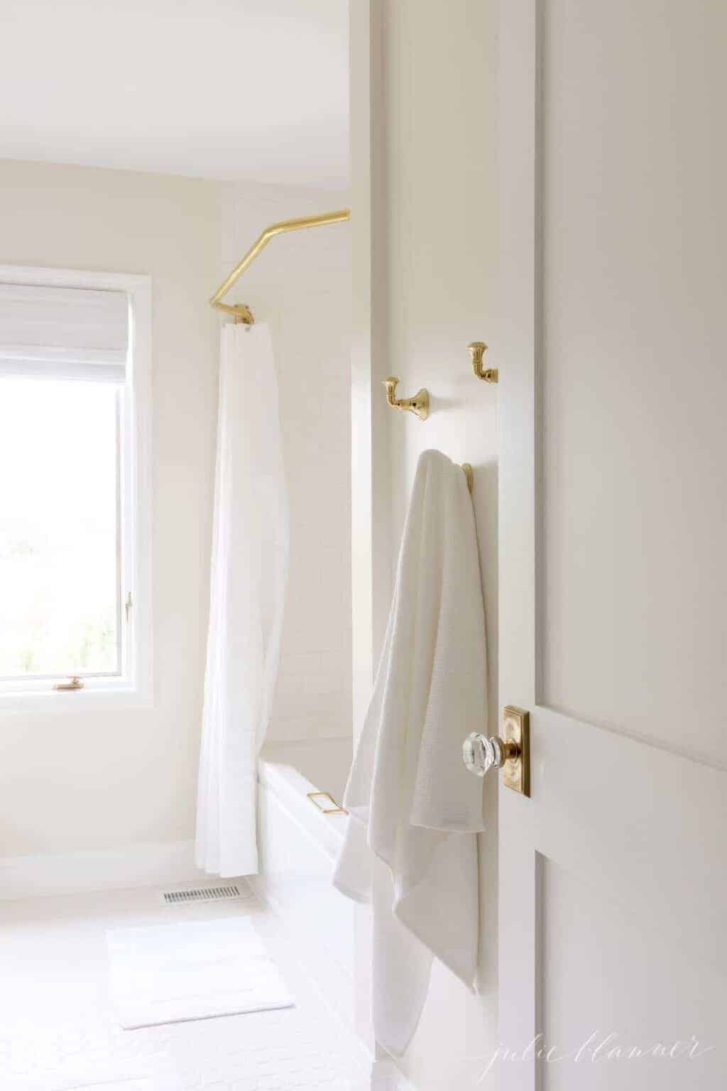 一扇白色震教徒风格的门，带有黄铜门把手，通往浴室。