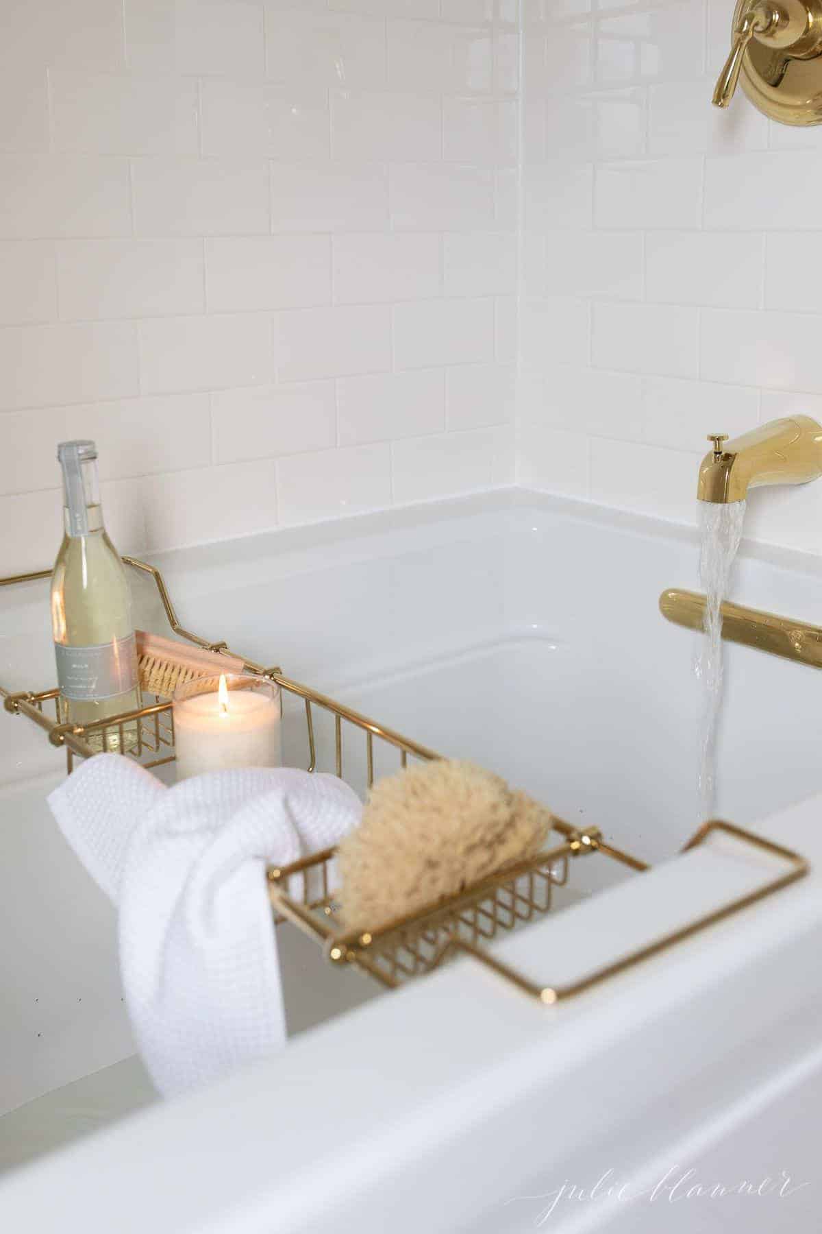 白色的浴缸被白色的地铁瓷砖和黄铜配件包围。