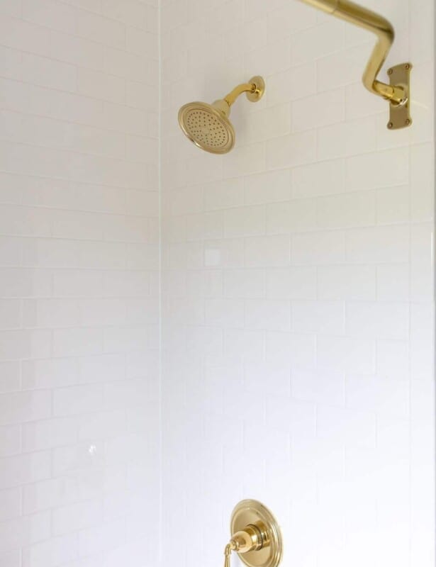 白色的地铁瓷砖淋浴，带有黄铜硬件。